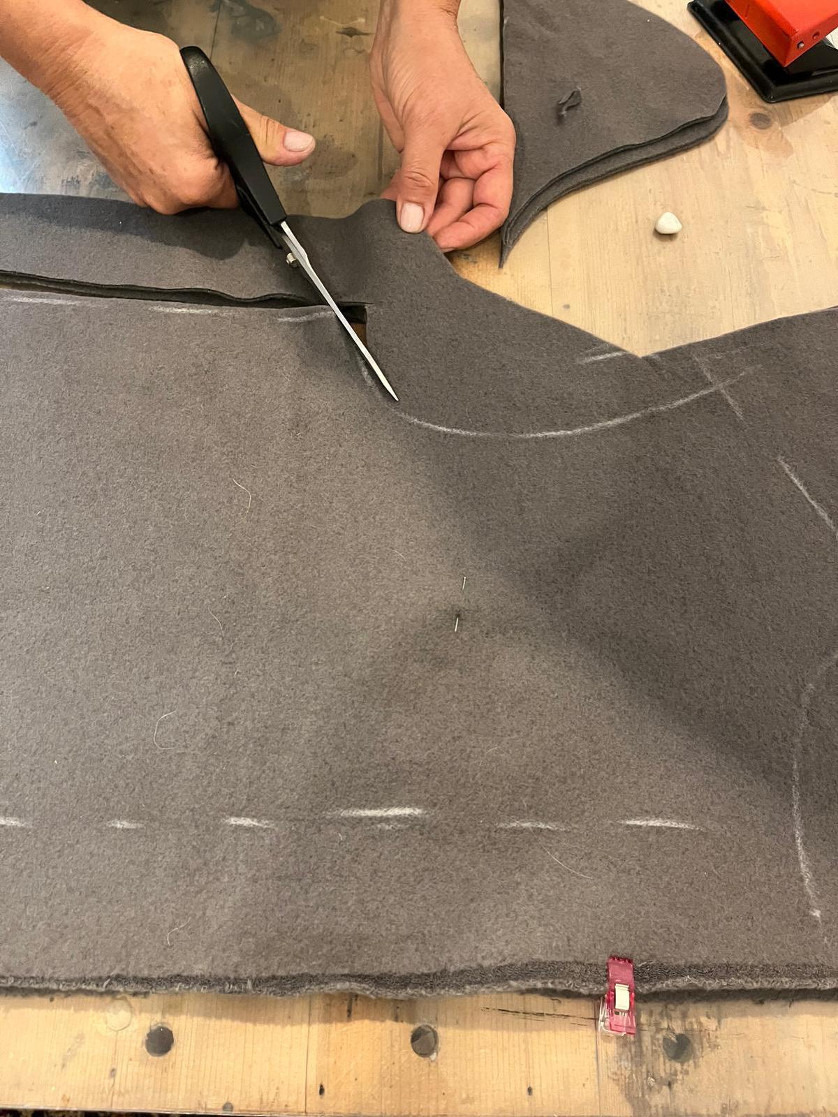 Il taglio a forbice di un cappotto in lana cotta sul tavolo dell'atelier natuRa.Ely ad Arco